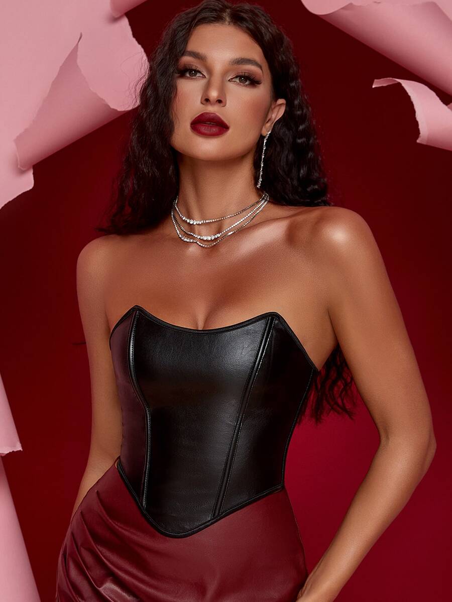 Women's black strapless PU bustier crop top featuring a lace-up back, grommet eyelet details, and an asymmetrical handkerchief hem.