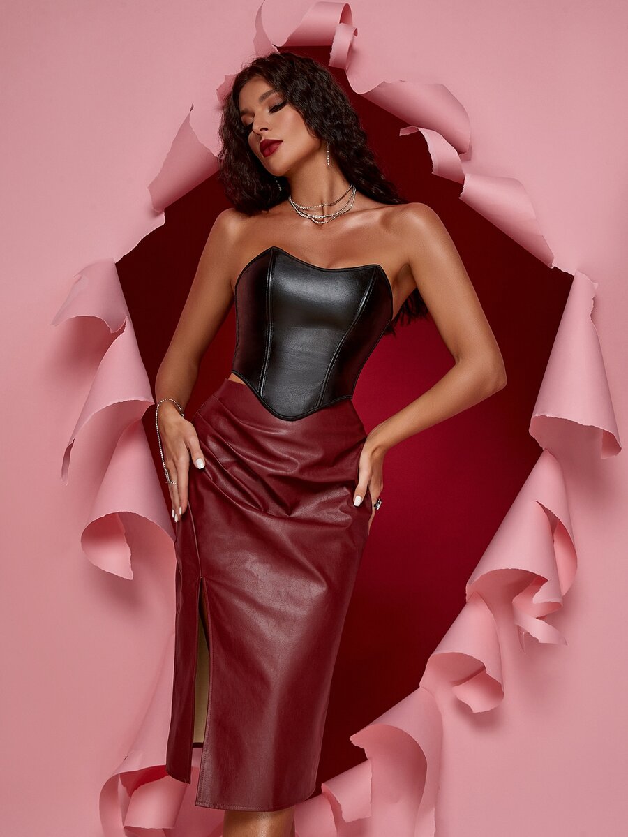 Women's black strapless PU bustier crop top featuring a lace-up back, grommet eyelet details, and an asymmetrical handkerchief hem.