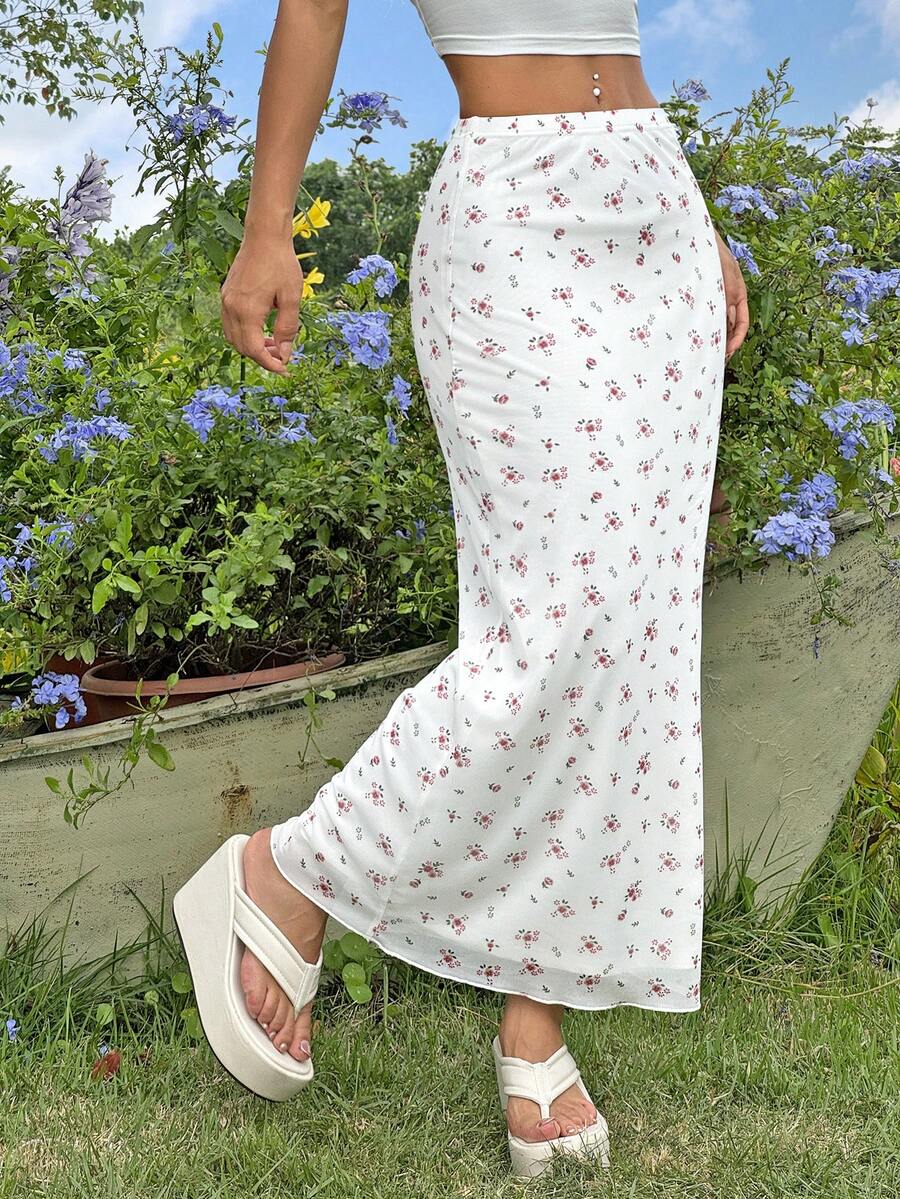White ditsy floral pattern bodycon midi skirt with split thigh detail and boho mermaid silhouette on a model.