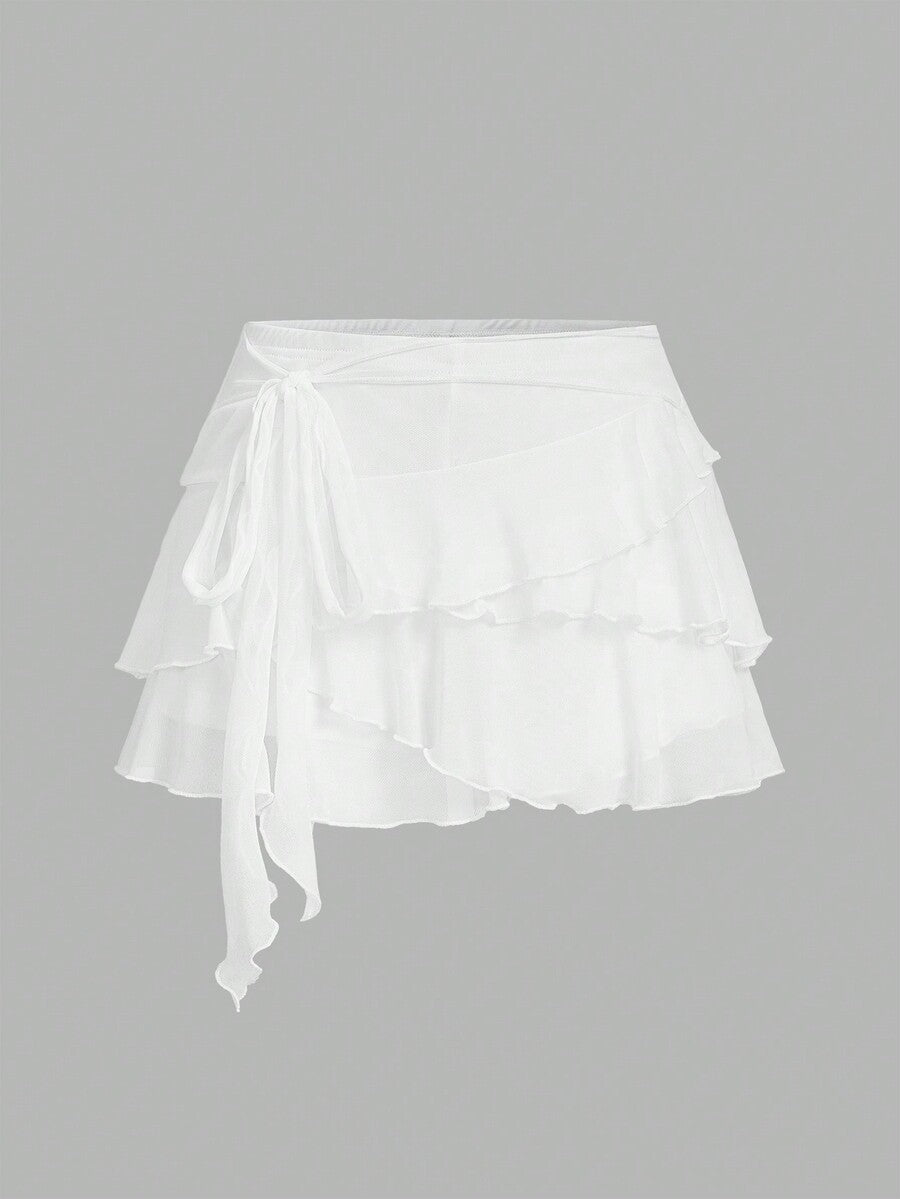 White tiered ruffle trim mini skirt for women with low waist, knot detail, mesh fabric, and casual Y2K boho design.
