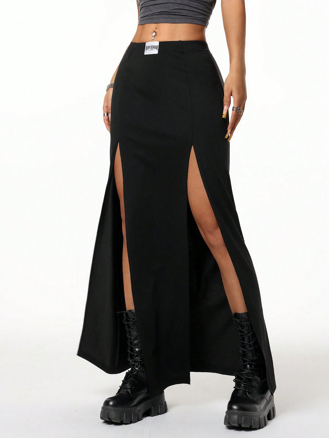 Women's black high waist long skirt with split thigh slit, zipper, and letter patch detail made from knitted stretch fabric.