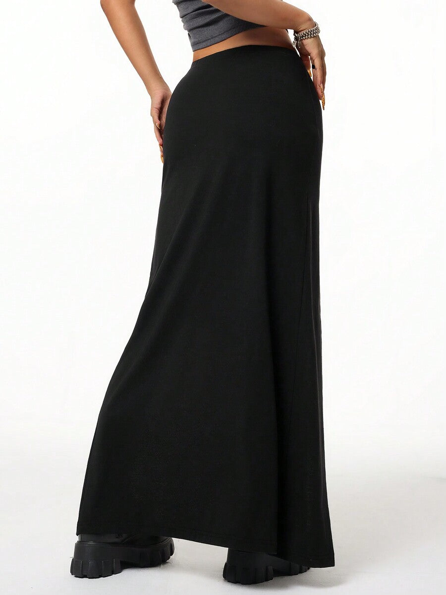 Women's black high waist long skirt with split thigh slit, zipper, and letter patch detail made from knitted stretch fabric.