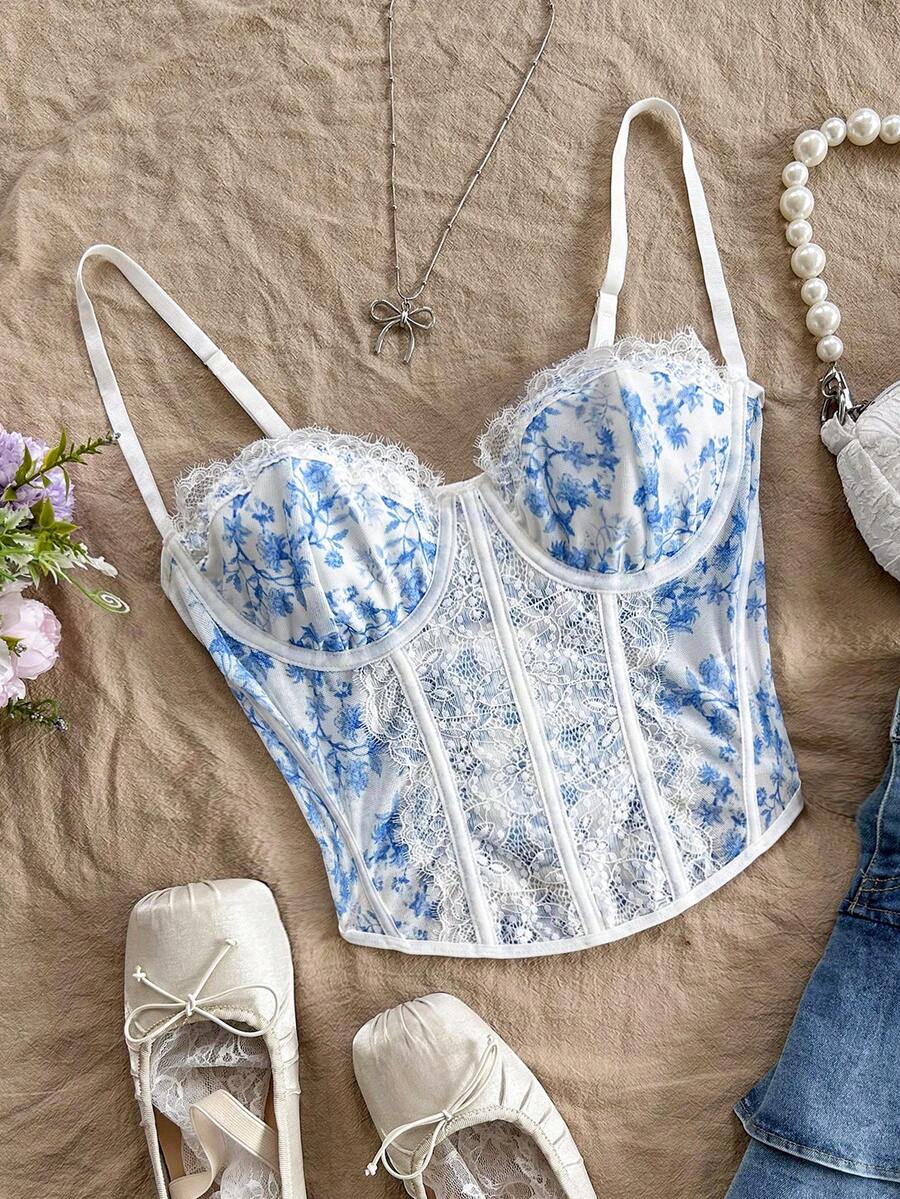 Women's lace bustier camisole top with spaghetti straps, contrast lace, lace-up detail, and an asymmetrical hem in a slim fit design.