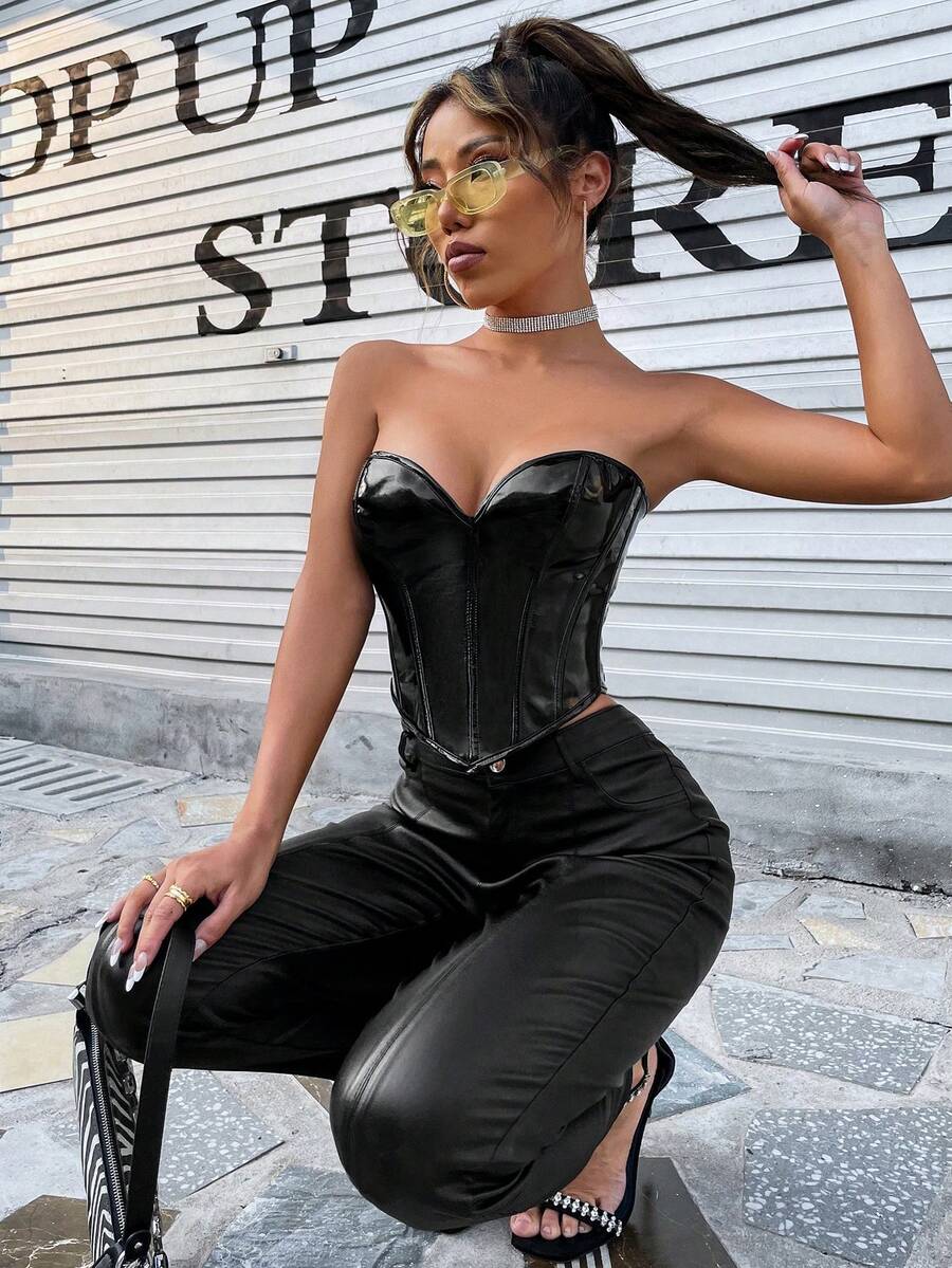 Black PU leather lace-up bustier crop top for women by Apperloth featuring a strapless asymmetrical hem with grommet eyelets.