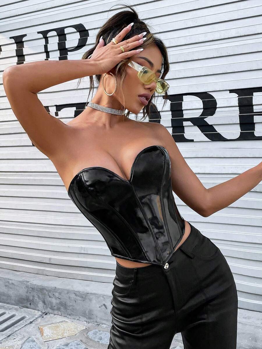 Black PU leather lace-up bustier crop top for women by Apperloth featuring a strapless asymmetrical hem with grommet eyelets.