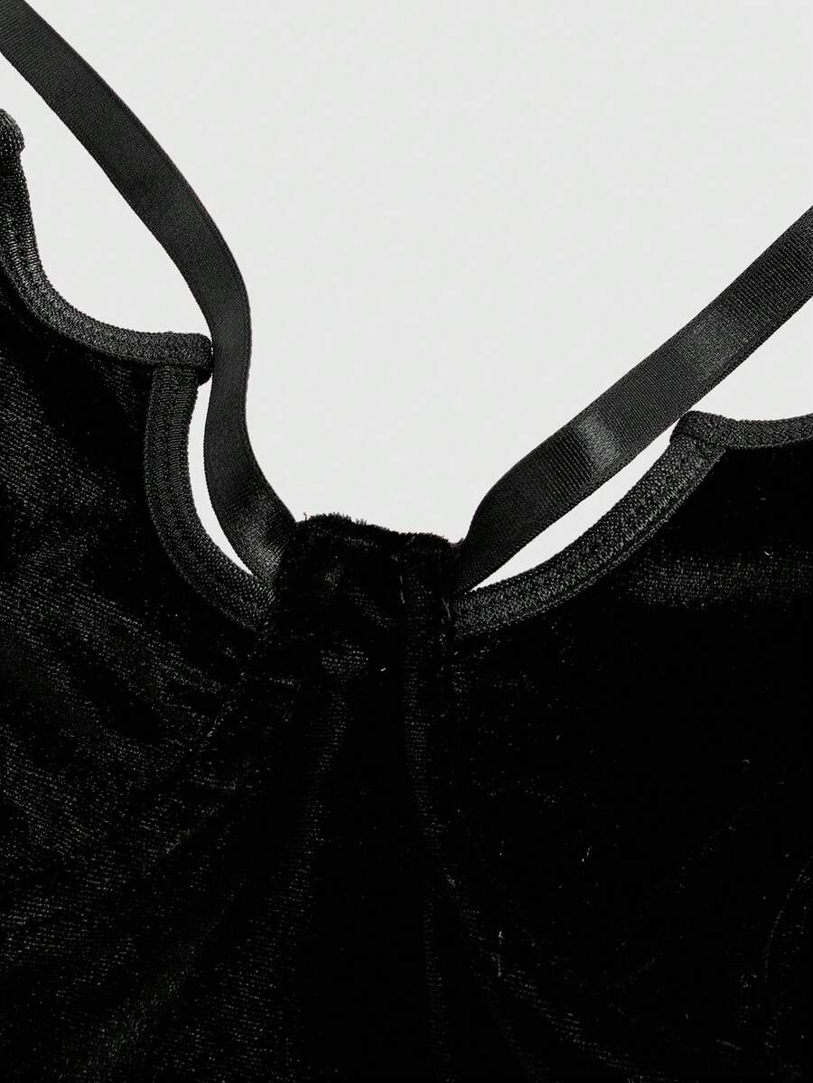 A women's black velvet crop camisole top featuring criss-cross shoulder straps, asymmetrical cut-out details, and a sleeveless vest neckline.