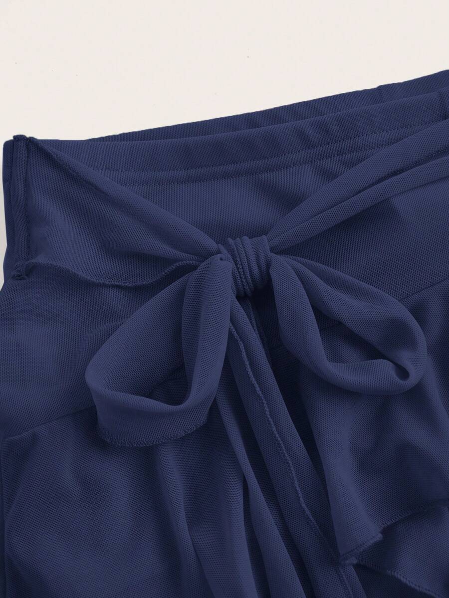 White tiered ruffle trim mini skirt for women with low waist, knot detail, mesh fabric, and casual Y2K boho design.