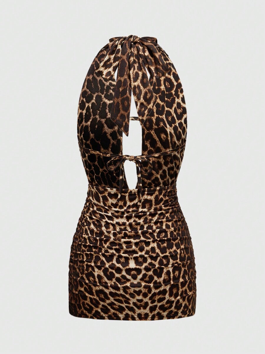 Black halter bodycon mini dress for women featuring a backless cut-out design, ruched detail, and a rhinestone cross pendant.