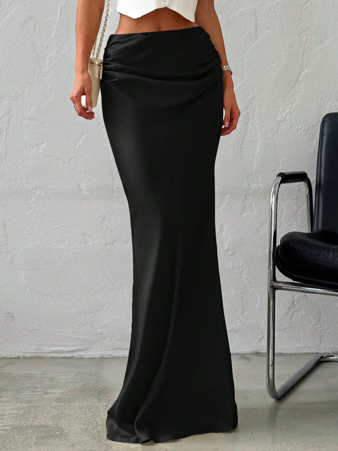 Women's black solid satin maxi skirt featuring an asymmetrical ruched design, ultra low waist, straight fit, and zipper closure.