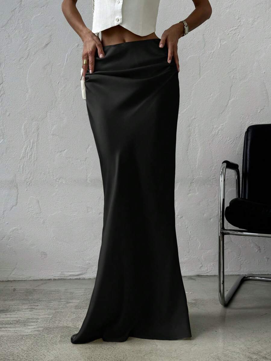 Women's black solid satin maxi skirt featuring an asymmetrical ruched design, ultra low waist, straight fit, and zipper closure.