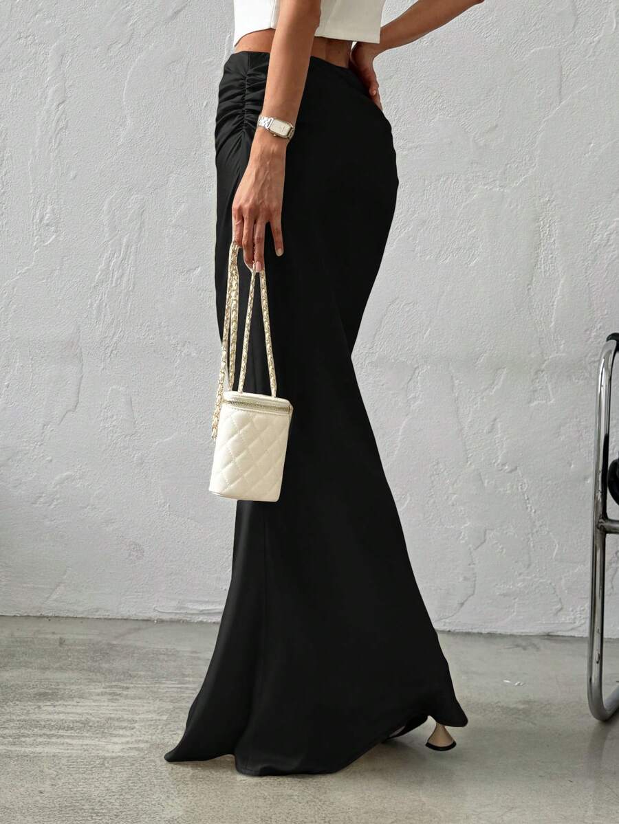 Women's black solid satin maxi skirt featuring an asymmetrical ruched design, ultra low waist, straight fit, and zipper closure.