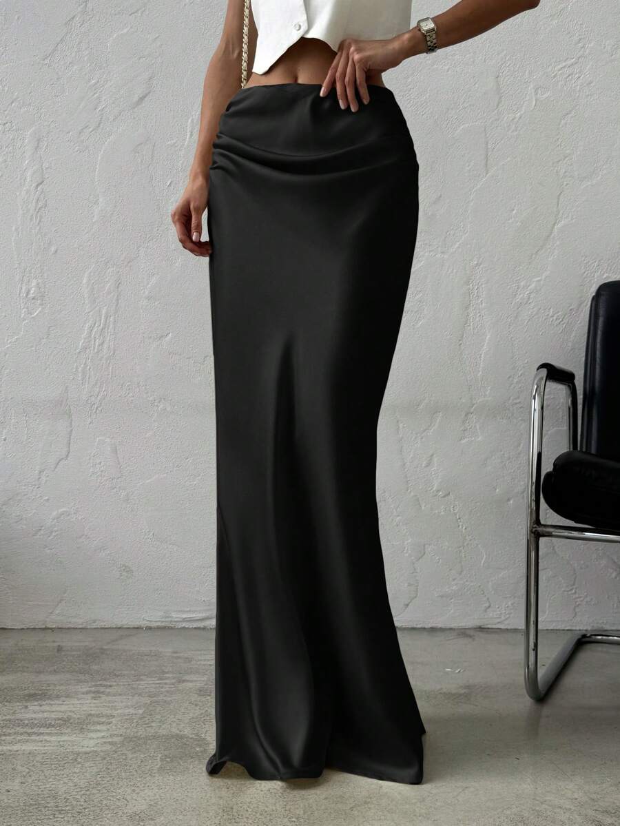 Women's black solid satin maxi skirt featuring an asymmetrical ruched design, ultra low waist, straight fit, and zipper closure.