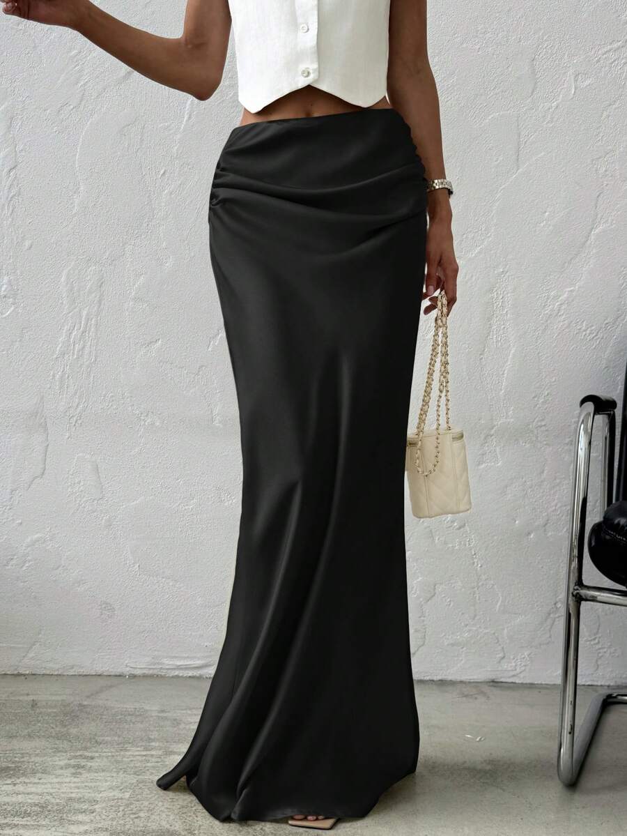 Women's black solid satin maxi skirt featuring an asymmetrical ruched design, ultra low waist, straight fit, and zipper closure.