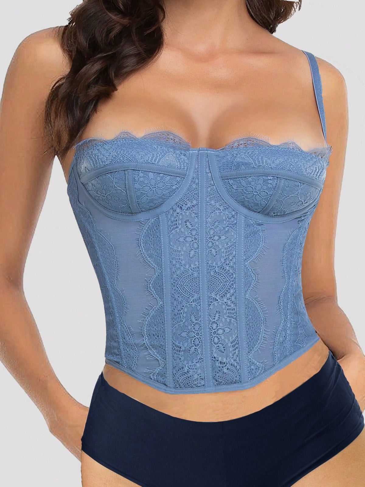 Black lace bustier corset top for women with asymmetrical contrast lace, lace-up detail, sleeveless crop cut, and light support.