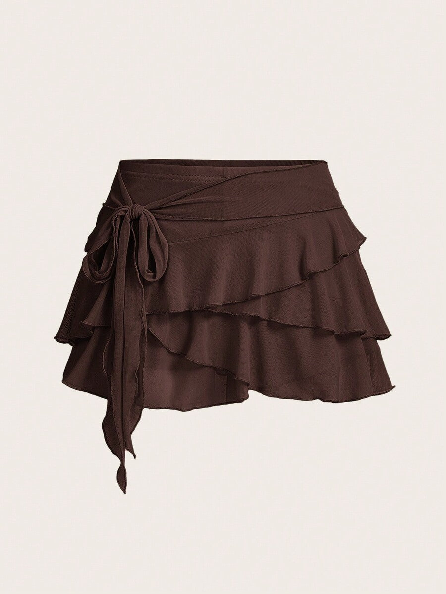 White tiered ruffle trim mini skirt for women with low waist, knot detail, mesh fabric, and casual Y2K boho design.