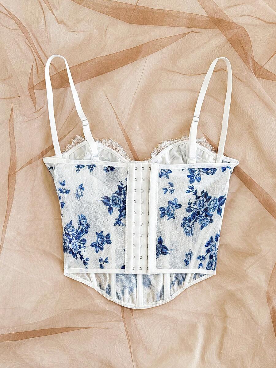 Women's lace bustier camisole top with spaghetti straps, contrast lace, lace-up detail, and an asymmetrical hem in a slim fit design.