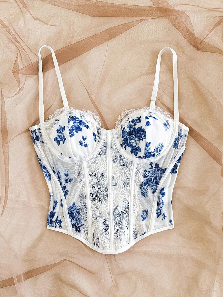 Women's lace bustier camisole top with spaghetti straps, contrast lace, lace-up detail, and an asymmetrical hem in a slim fit design.