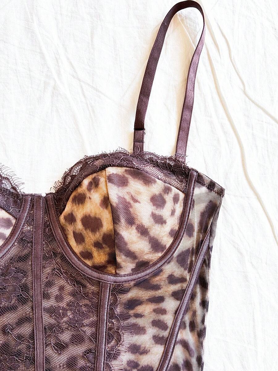 Women's lace bustier camisole top with spaghetti straps, contrast lace, lace-up detail, and an asymmetrical hem in a slim fit design.