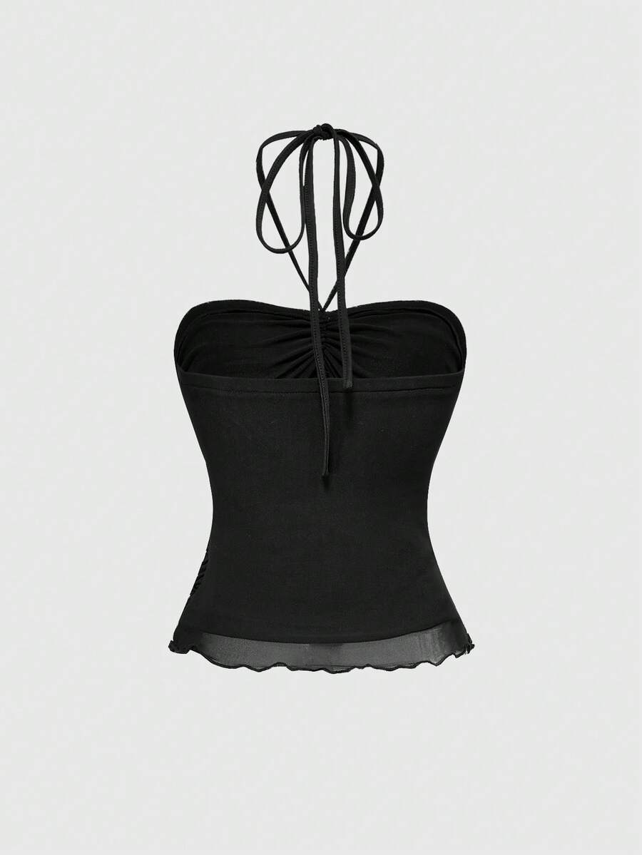 Women's black halter crop top featuring a backless cut, front ring detail, knot accent, asymmetrical hem, and high-stretch mesh fabric.