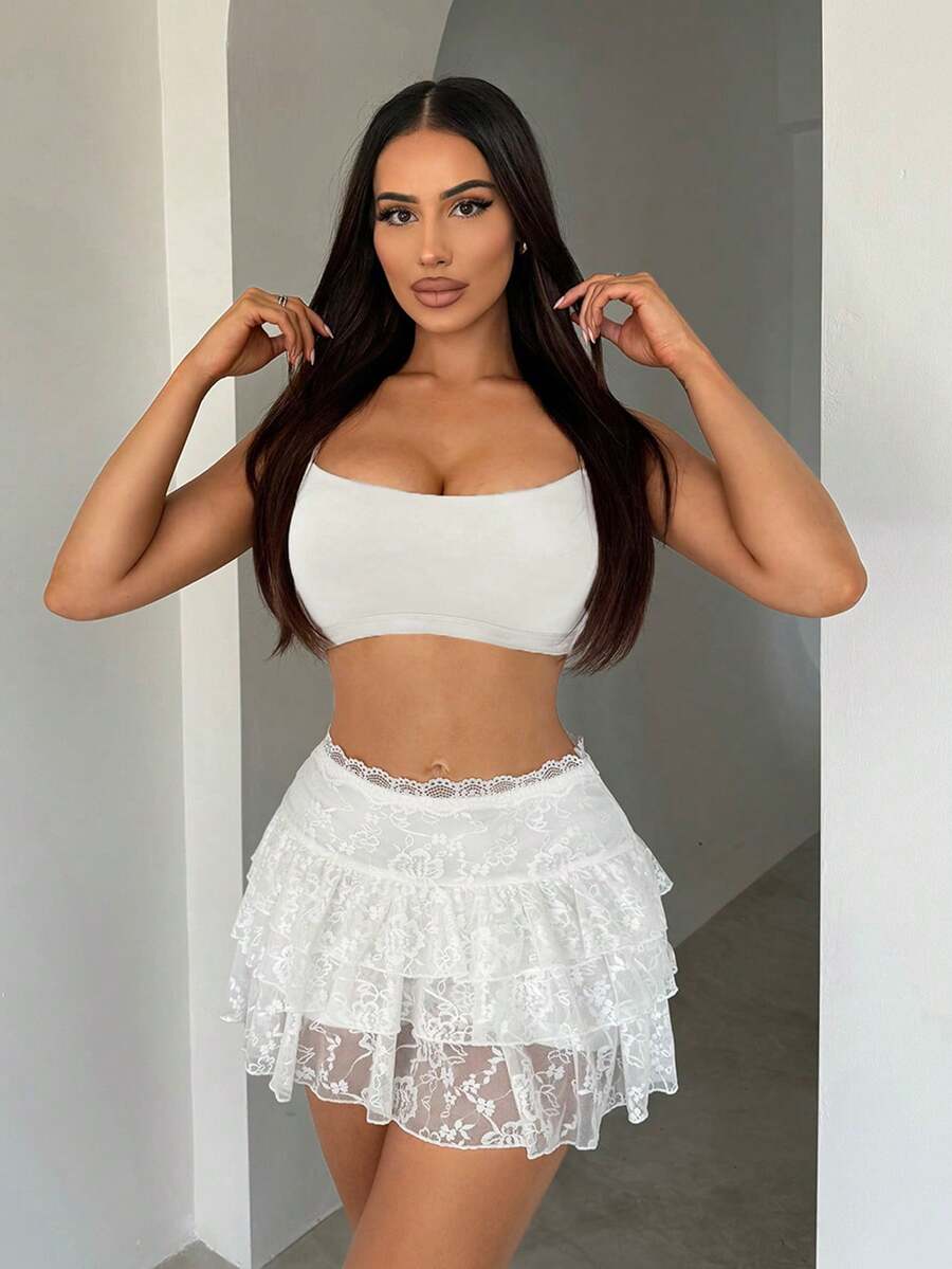 Women's white lace tiered mini skort featuring a low waist, ruffle hem, contrast lace detail, and lined stretch fabric.