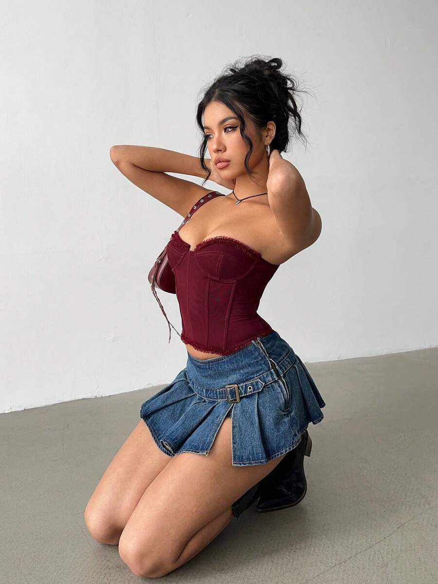 Women's blue denim pleated mini skirt skort featuring a low waist fit with zipper and grommet eyelet details.