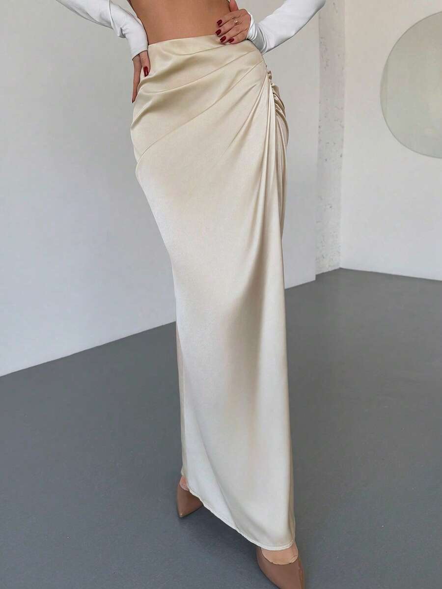Women's solid color ruched satin maxi skirt featuring an asymmetrical wrap design and side slit.