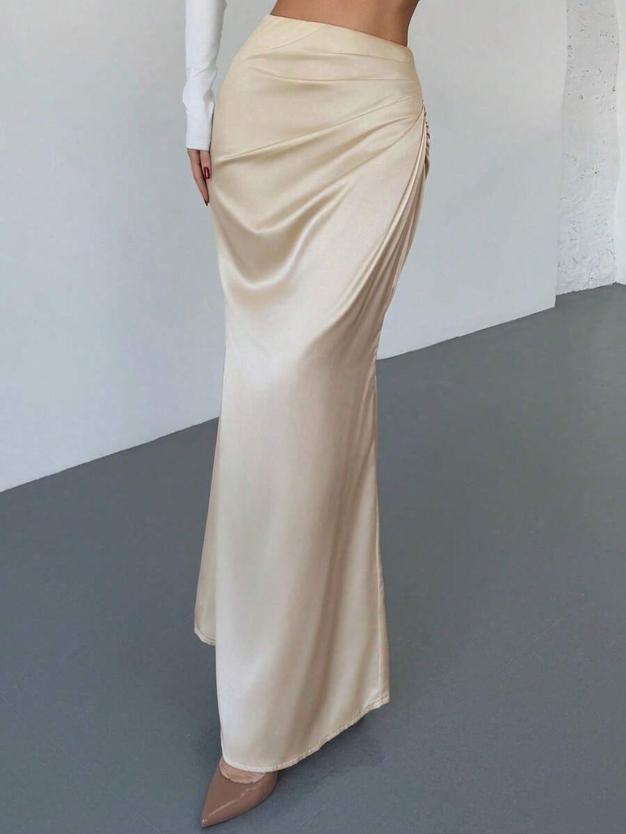 Women's solid color ruched satin maxi skirt featuring an asymmetrical wrap design and side slit.