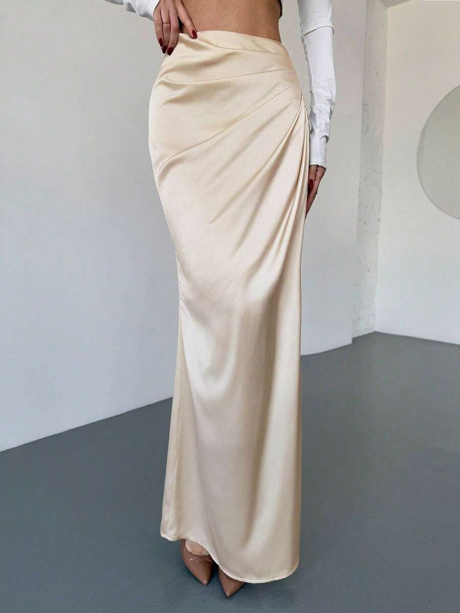 Women's solid color ruched satin maxi skirt featuring an asymmetrical wrap design and side slit.