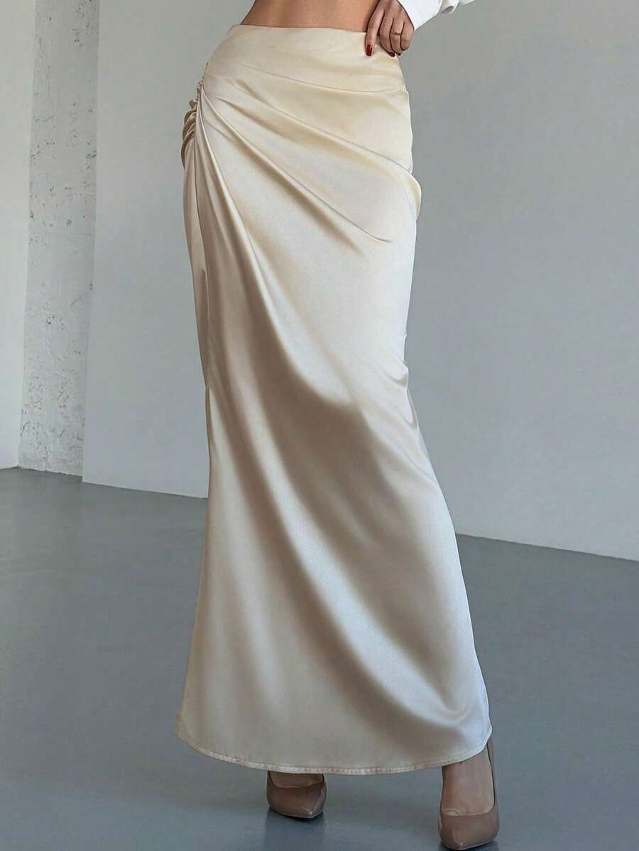 Women's solid color ruched satin maxi skirt featuring an asymmetrical wrap design and side slit.