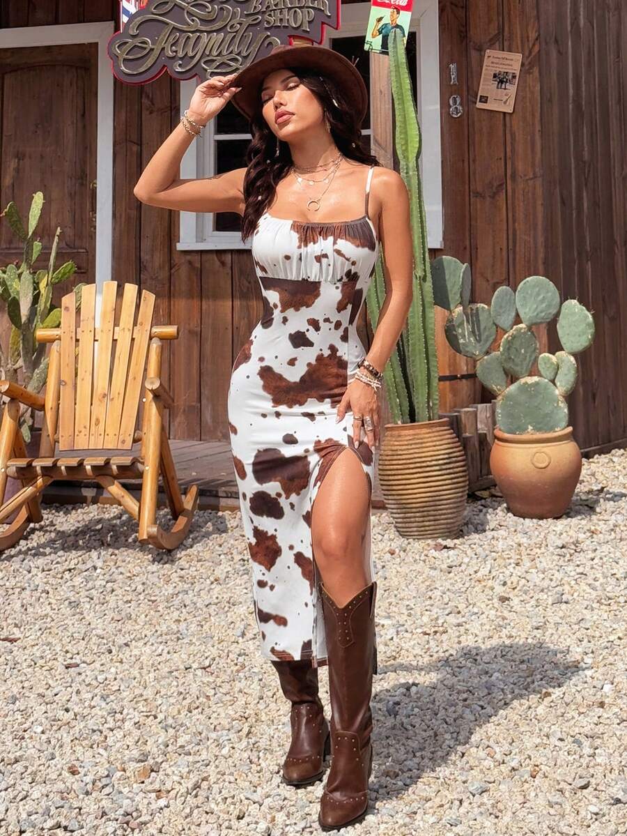 Black and white cow print cami midi dress for women featuring spaghetti straps, ruched bust, backless detail, and a split thigh hem.