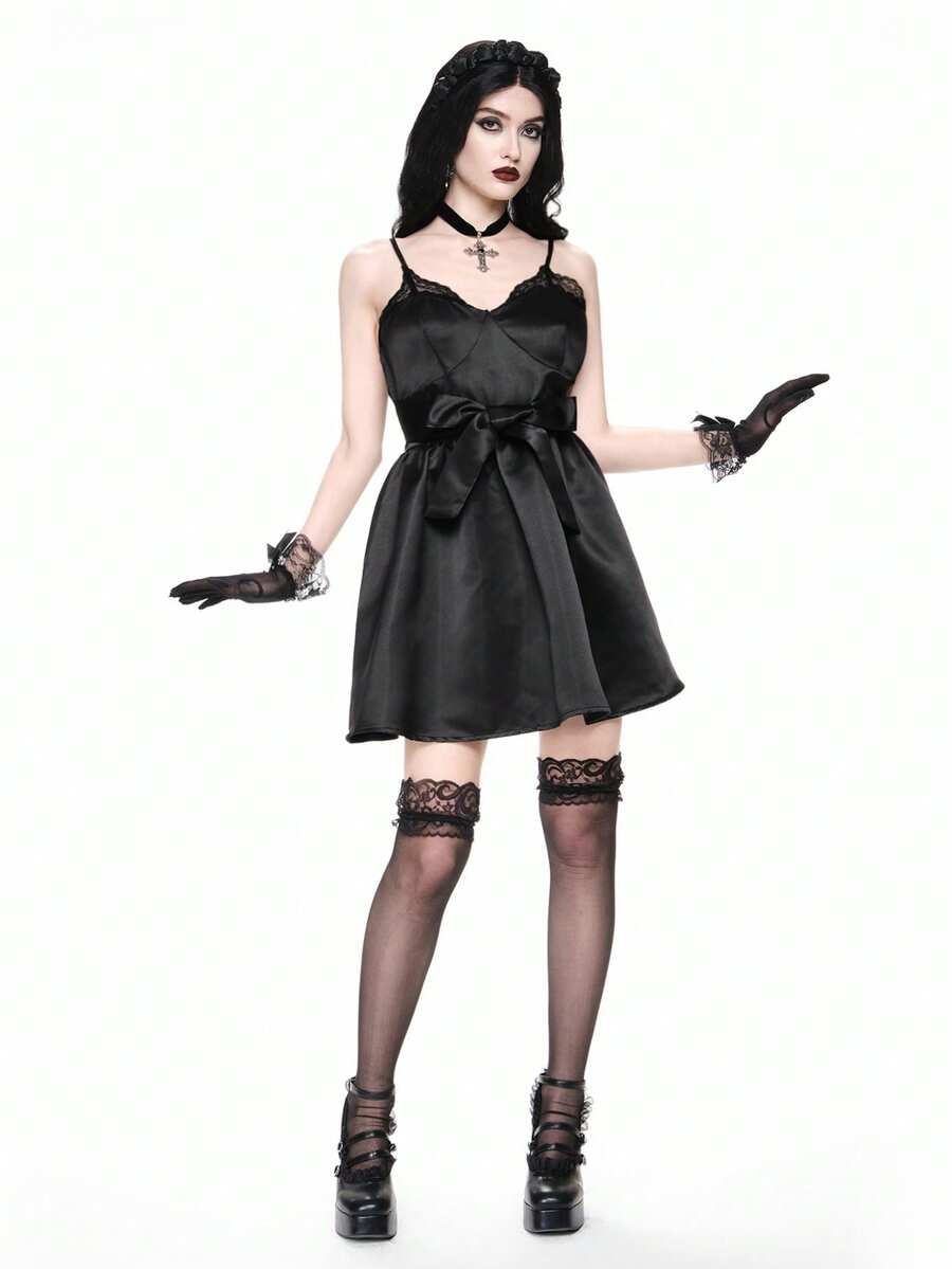 Front view of women wearing black gothic satin mini dress with contrast lace trim, bow accent, spaghetti straps, high waist, and tiered flared hem.