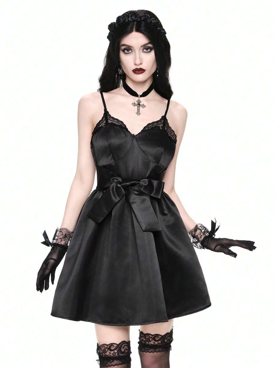 Front view of women wearing black gothic satin mini dress with contrast lace trim, bow accent, spaghetti straps, high waist, and tiered flared hem.