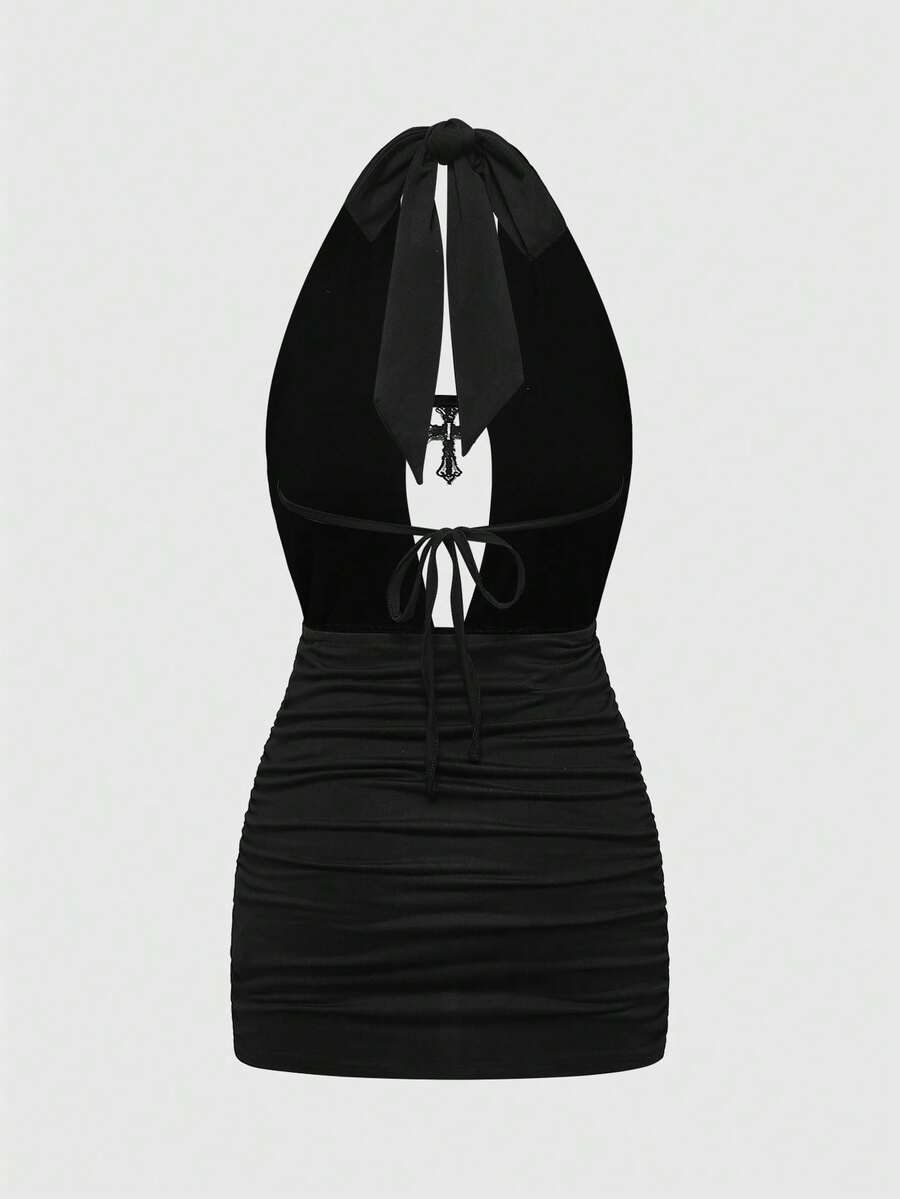 Black halter bodycon mini dress for women featuring a backless cut-out design, ruched detail, and a rhinestone cross pendant.