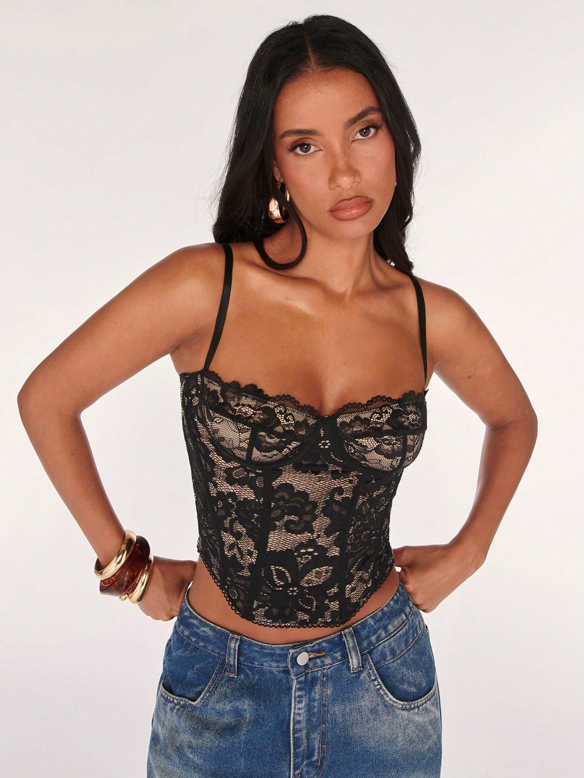 Black women’s lace cami top with spaghetti straps, contrast lace details, and an asymmetrical hem, styled as a slim-fit lined casual top.