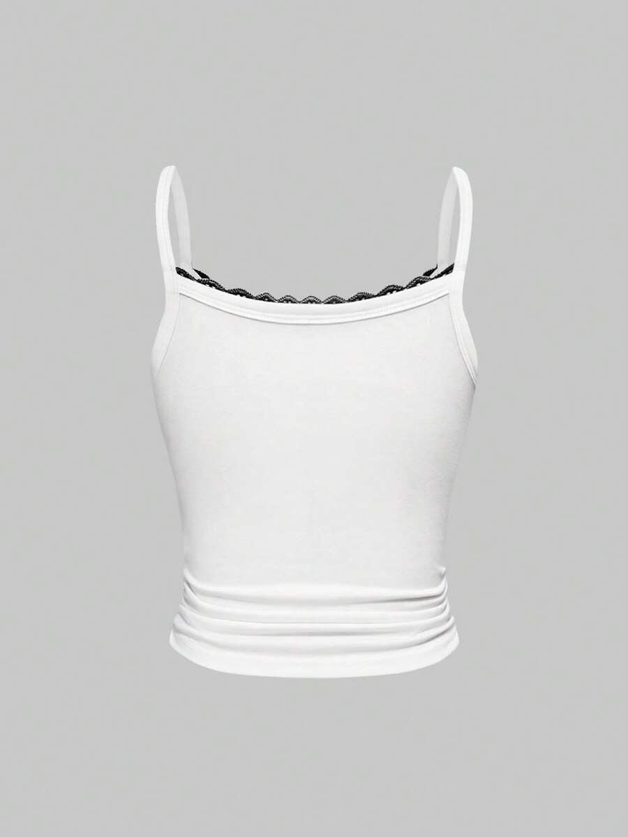 White crop cami top for women featuring spaghetti straps, contrast lace trim, bow detail, and frill trim.