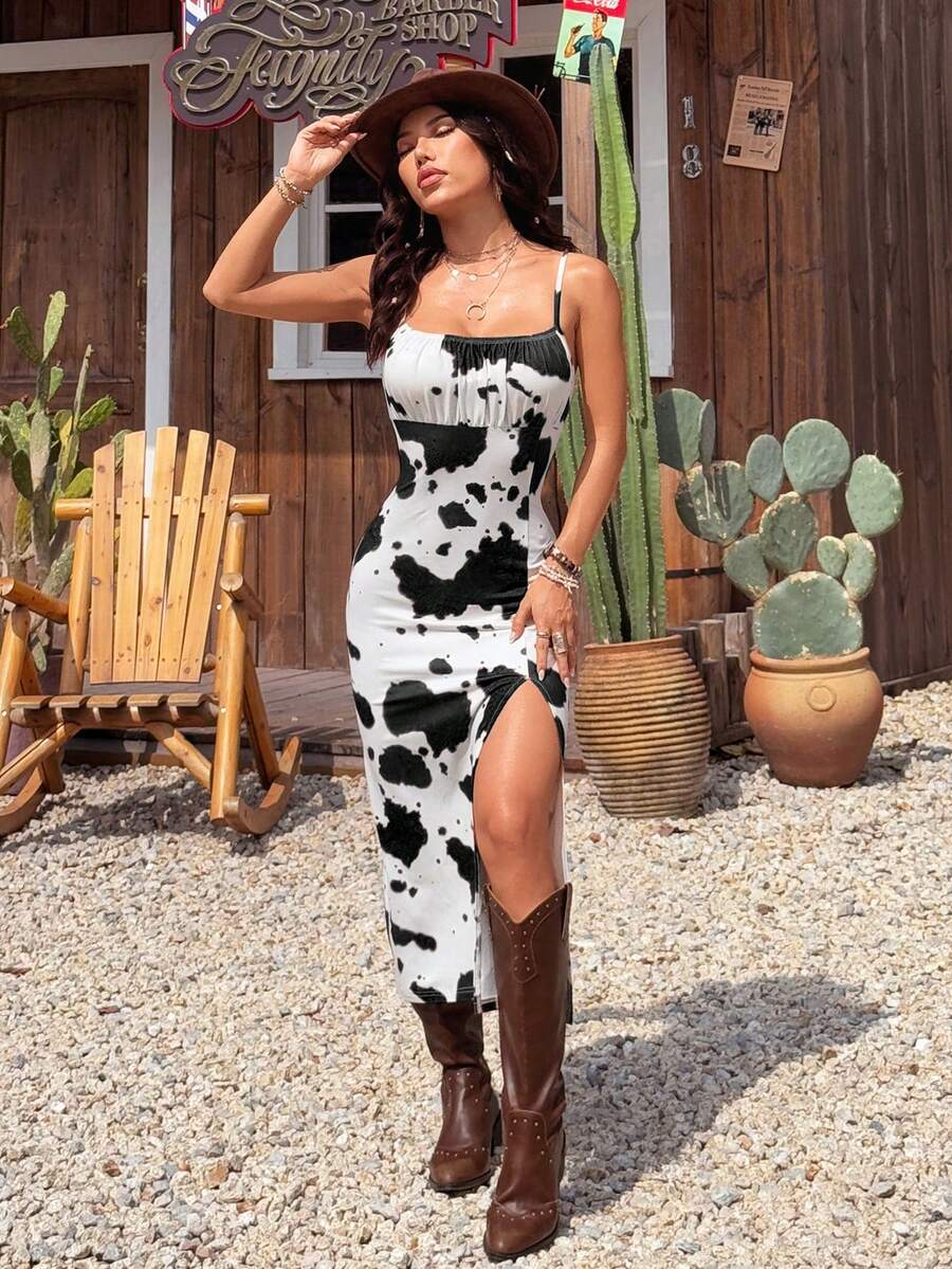 Black and white cow print cami midi dress for women featuring spaghetti straps, ruched bust, backless detail, and a split thigh hem.