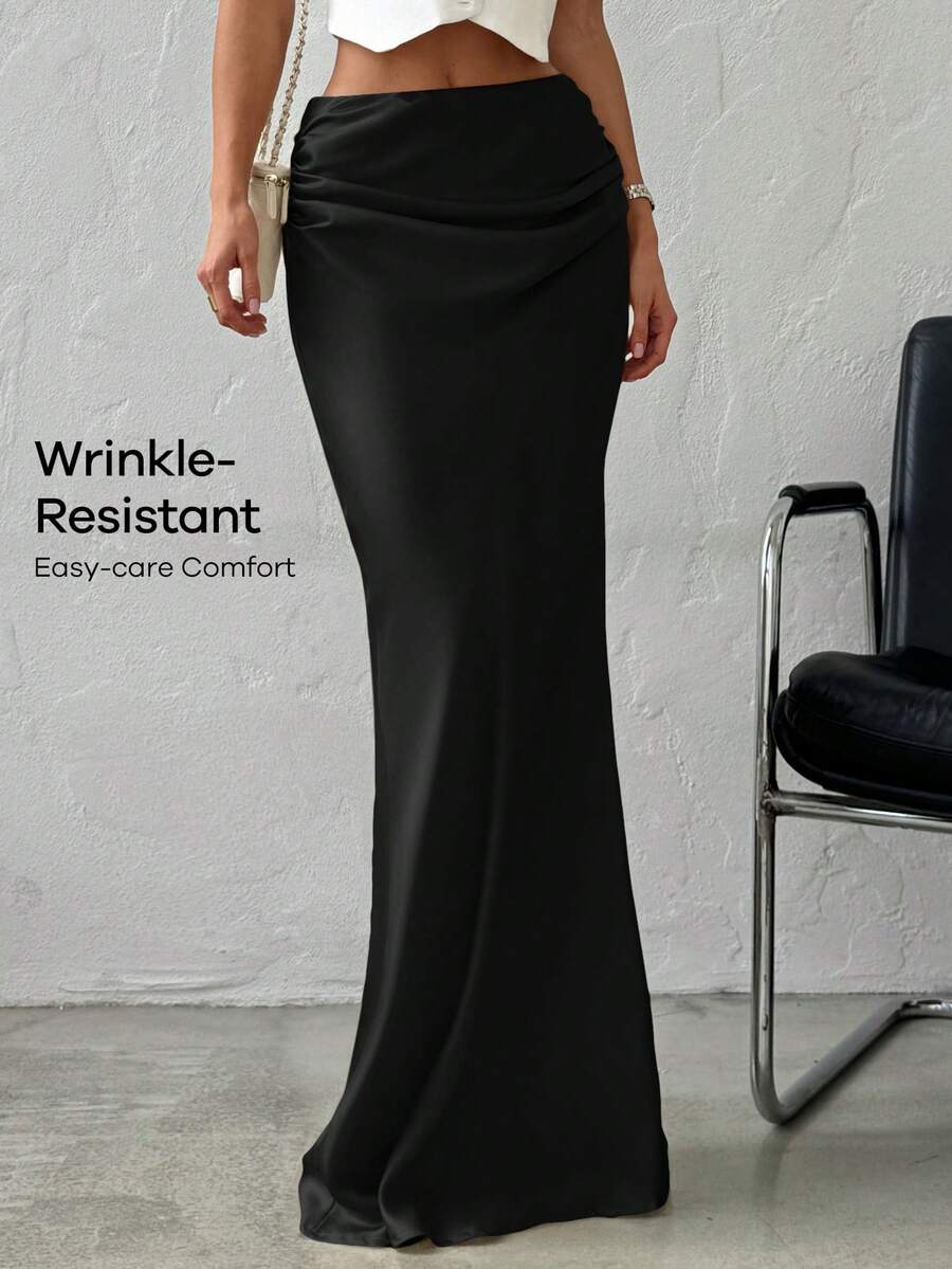 Women's black solid satin maxi skirt featuring an asymmetrical ruched design, ultra low waist, straight fit, and zipper closure.