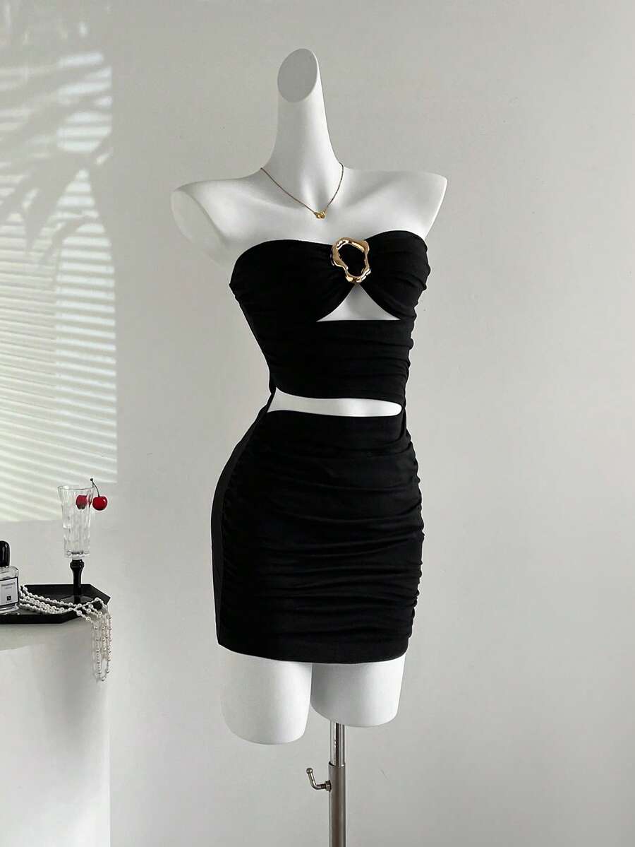 Women's black strapless bodycon mini dress featuring ruched detailing, cut-out design with ring accent, mid-waist pencil hem, and slim fit knitted stretch fabric.