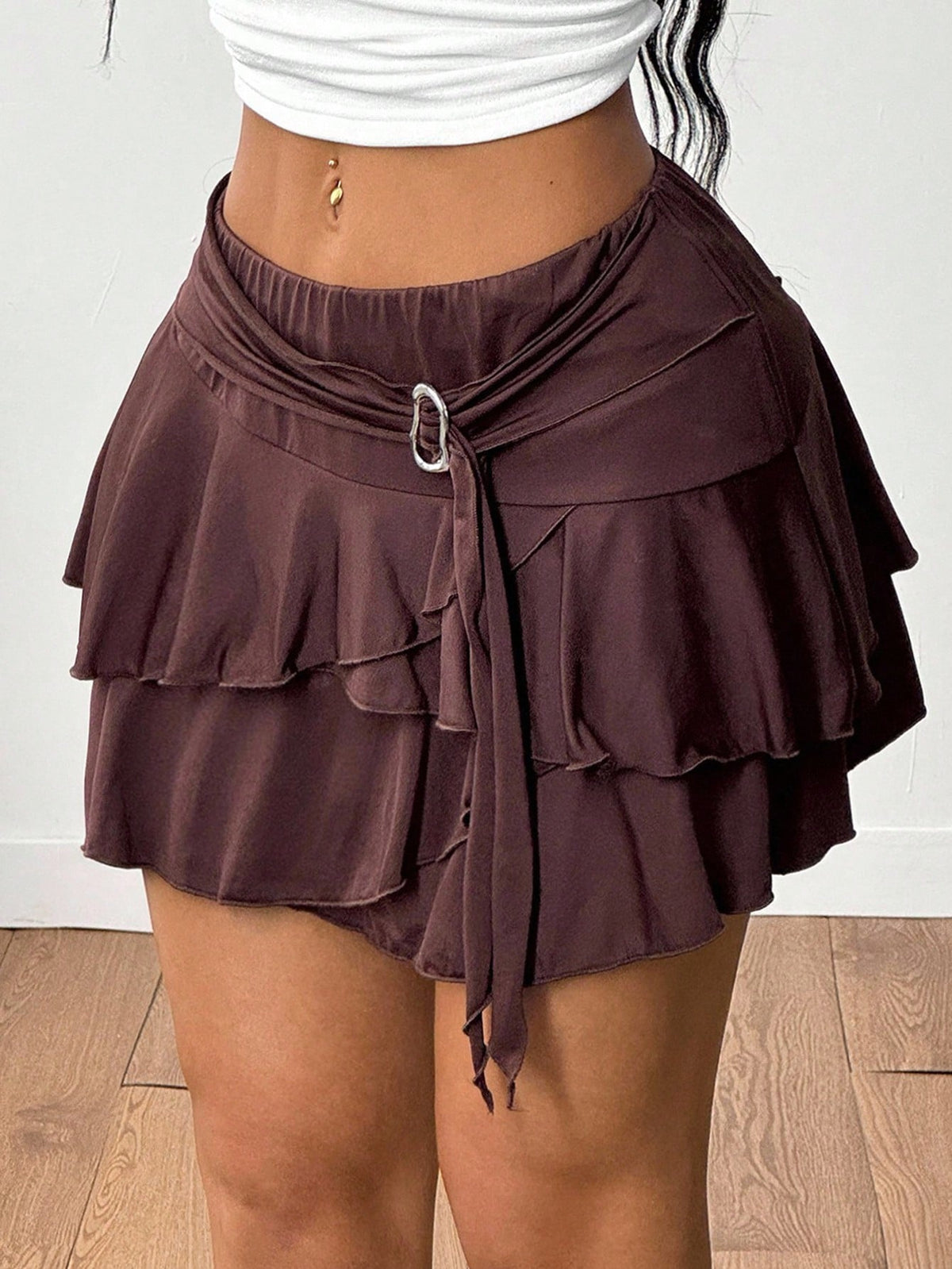 Black low waist tiered mini skirt featuring a ruffle hem and ring accent detail on knitted stretch fabric for women.