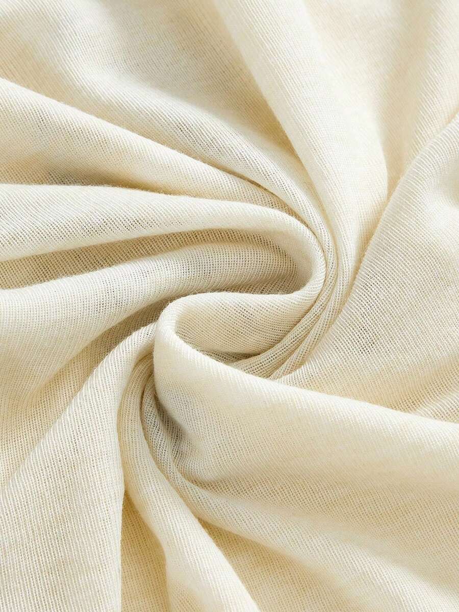 Beige asymmetric cami top for women featuring beaded details, fringe trim, knot accents, and round neck in high stretch knitted fabric.