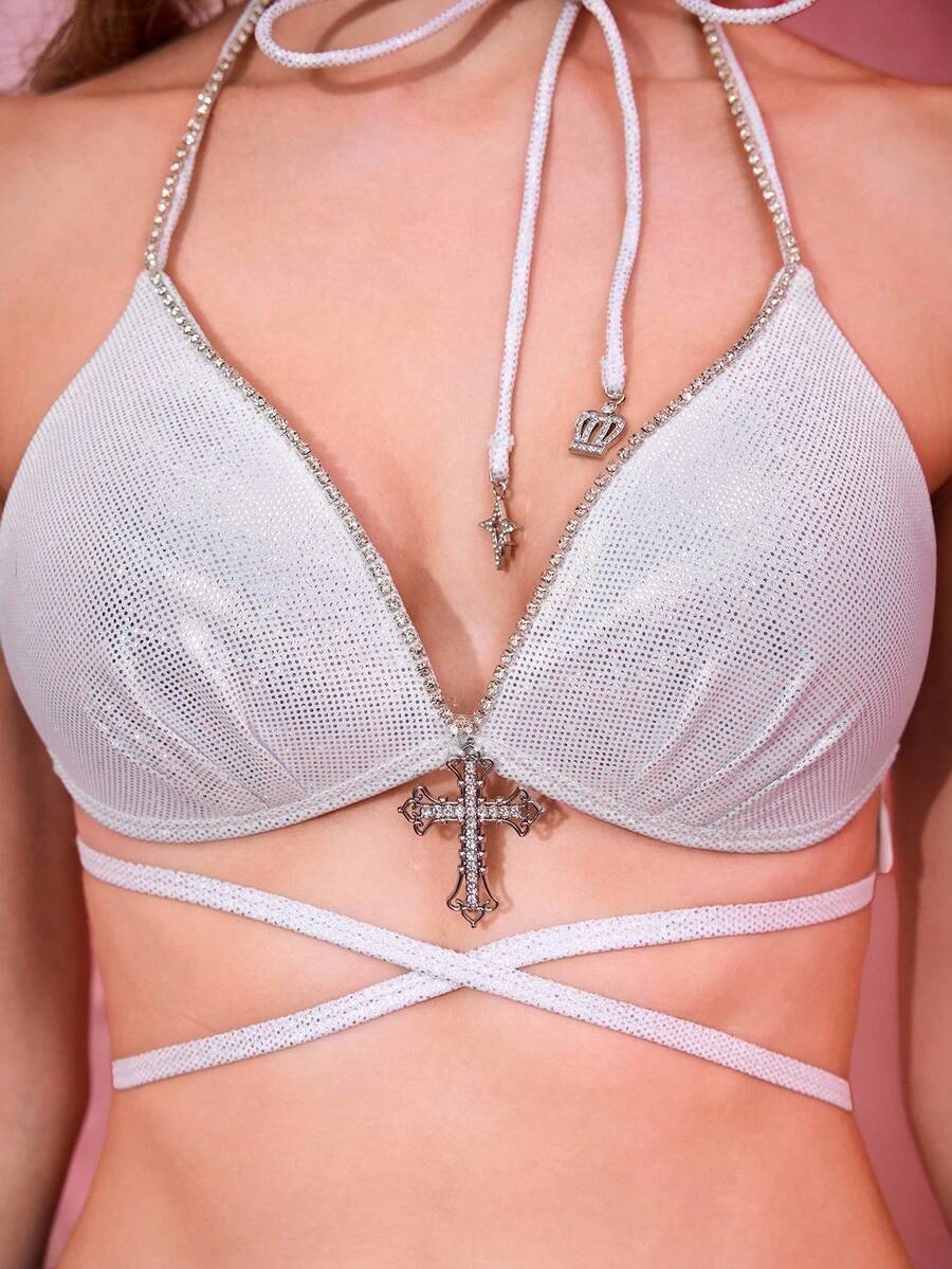 White criss cross halter crop top featuring a backless knitted design with thin spaghetti straps and an asymmetrical hem for women.