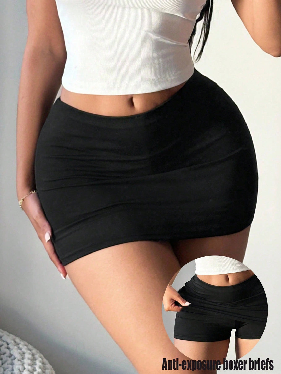 Front view of a woman wearing a sexy black bodycon mini skort featuring a low waist and built-in shorts for clubbing and night out outfits.