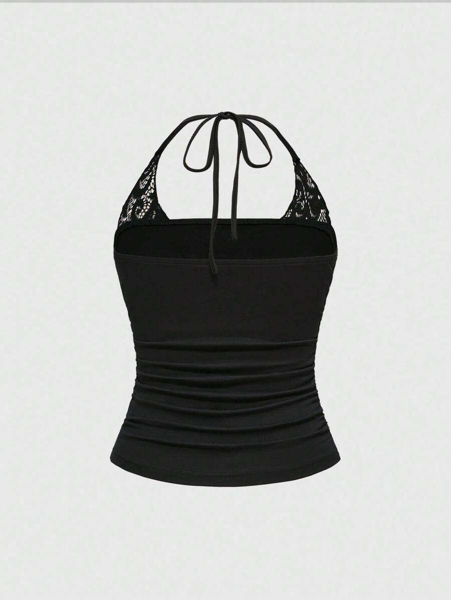 Woman wearing a black Y2K concert print 2-in-1 contrast lace halter crop top featuring a backless design with knot details.