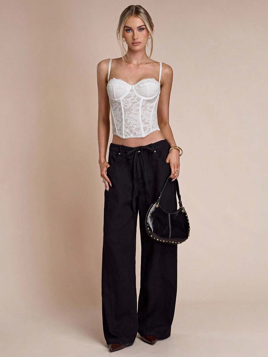 Black women’s lace cami top with spaghetti straps, contrast lace details, and an asymmetrical hem, styled as a slim-fit lined casual top.