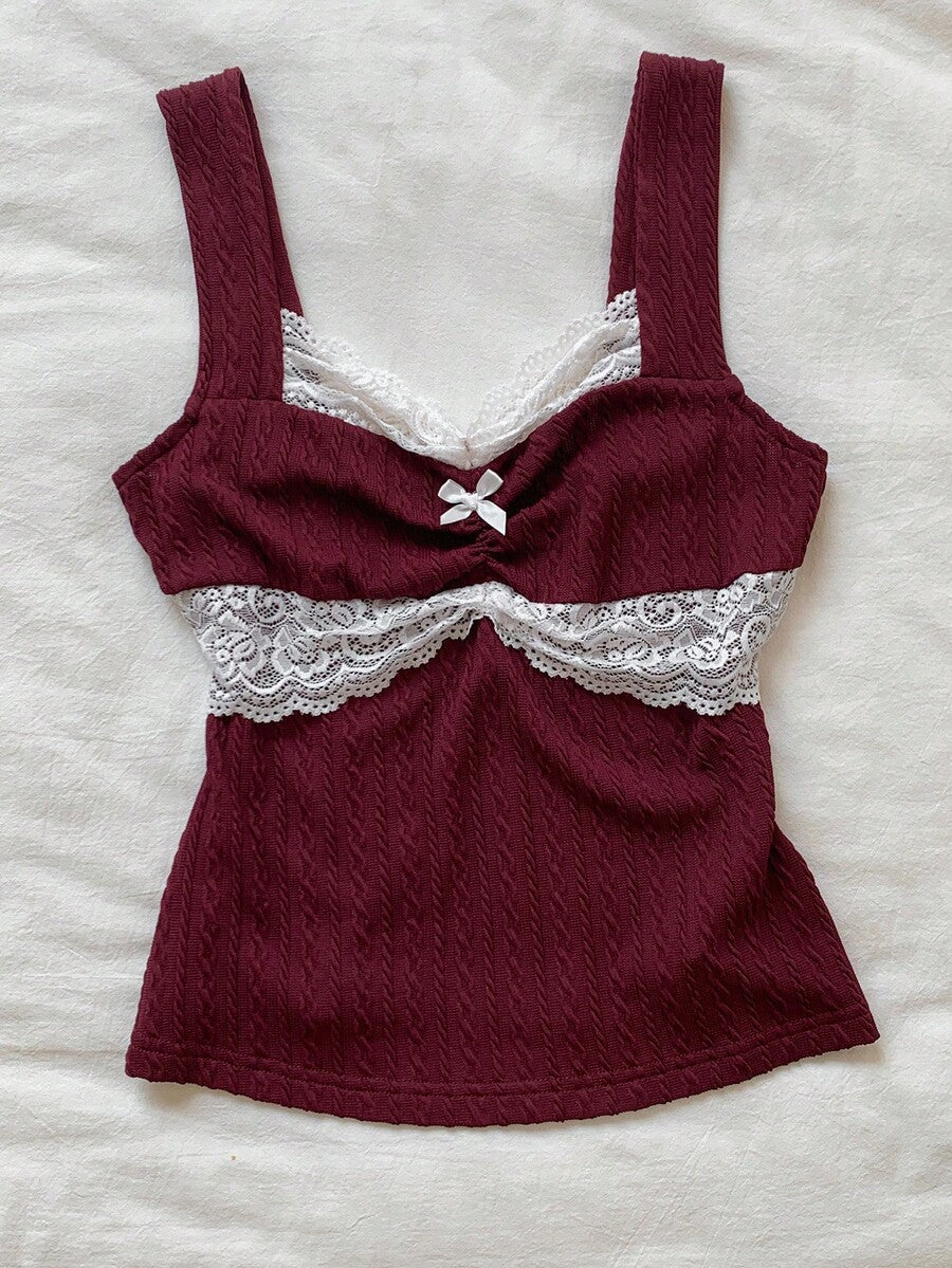 Black and white polka dot knit camisole tank top featuring delicate contrast lace trim, a cute bow accent at the sweetheart neckline, and slender shoulder straps.