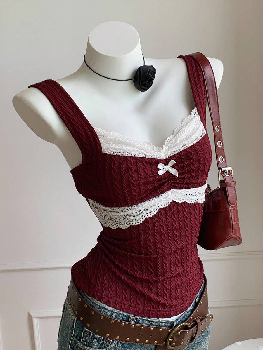 Black and white polka dot knit camisole tank top featuring delicate contrast lace trim, a cute bow accent at the sweetheart neckline, and slender shoulder straps.