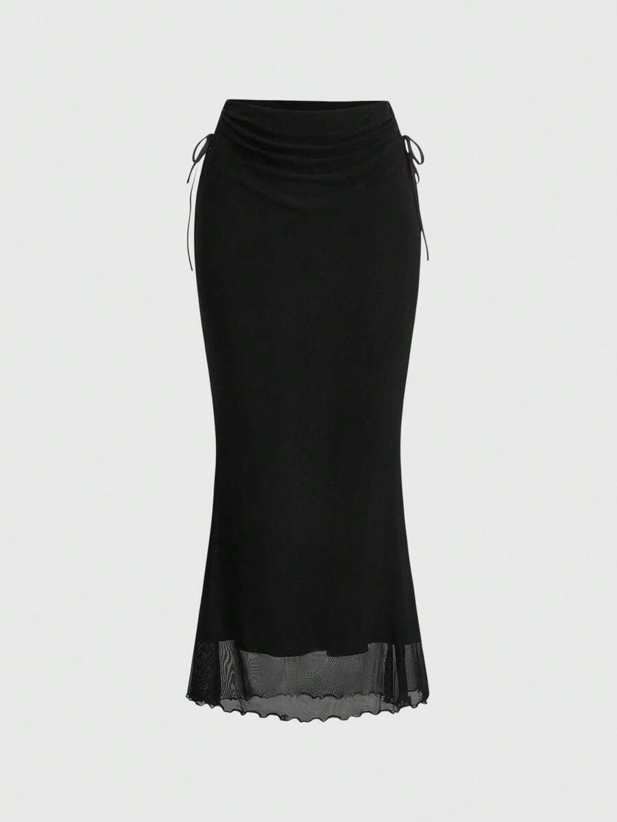 Woman wearing a solid black fairycore drawstring mermaid long skirt featuring ruched side detailing, lettuce trim, and a high side slit.