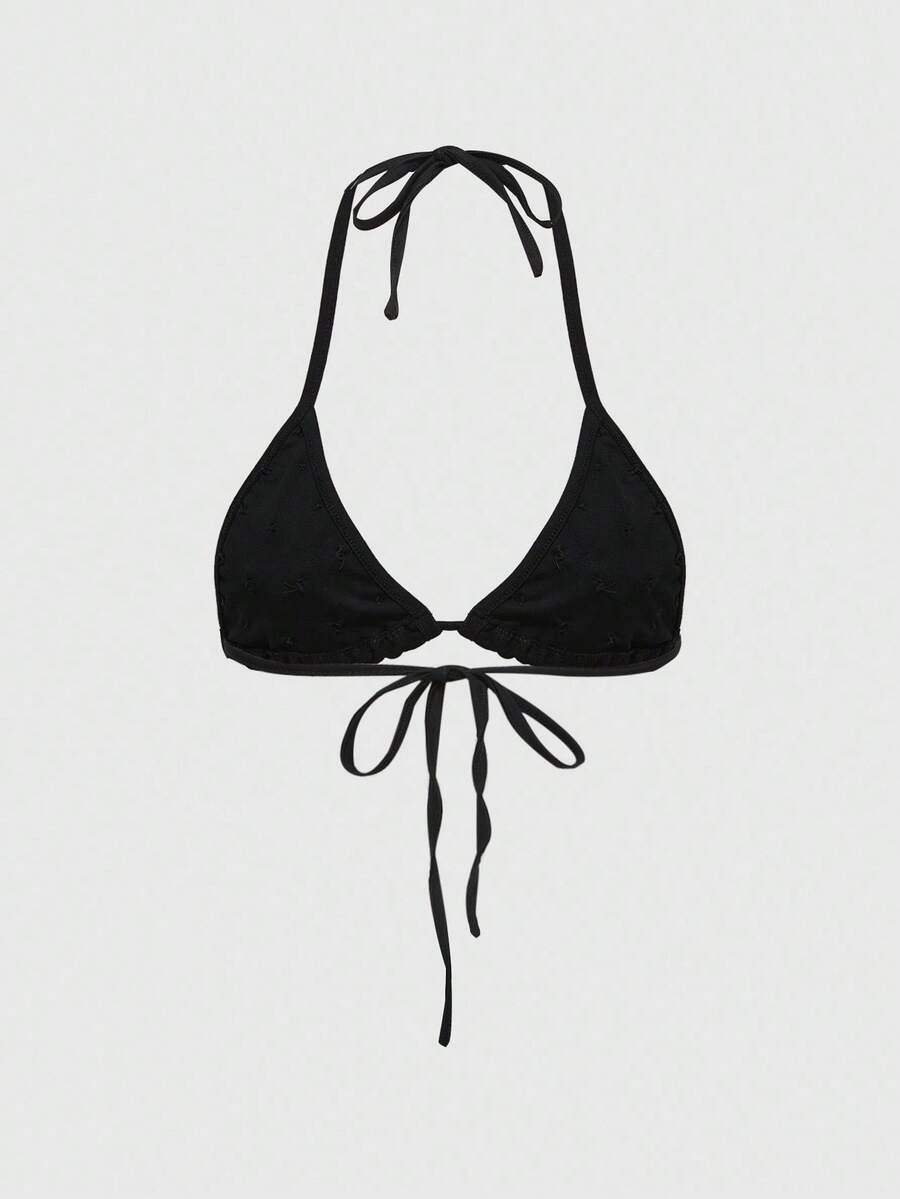 Black halter micro crop top featuring a backless tie-back design with shell button details on a woman.