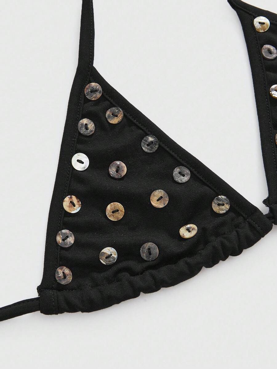 Black halter micro crop top featuring a backless tie-back design with shell button details on a woman.