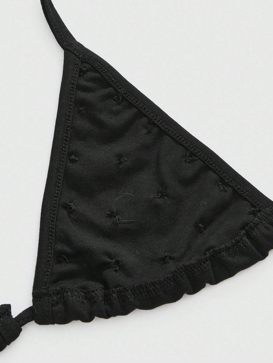 Black halter micro crop top featuring a backless tie-back design with shell button details on a woman.